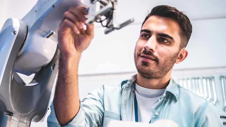 Ingeniero dentro de un laboratorio desarrollando un robot cómo solución a la automatización del trabajo.